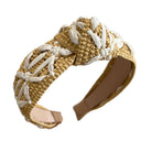 Beige and white woven headband held by a hand against a neutral background