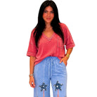 Woman wearing a red oversized shirt and blue pants with star designs on a white background