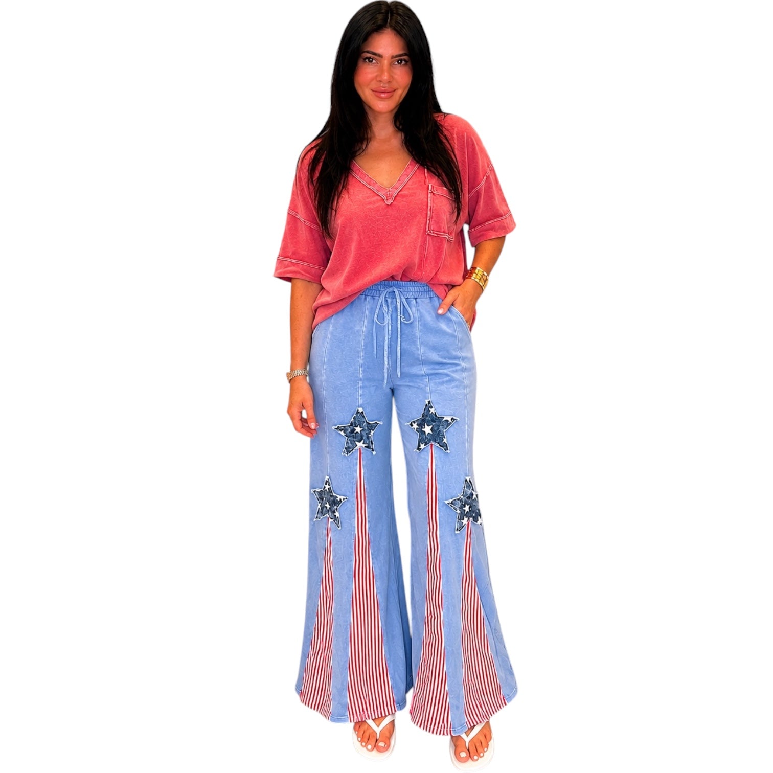 Woman wearing a red top and blue pants with star designs on a white background