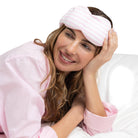Woman wearing a pink sleep mask on a white background