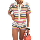 Person wearing a colorful striped outfit with a white collar, holding an orange handbag on a white background.