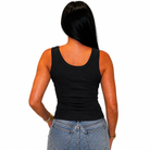 A woman viewed from the back wearing a fitted black sleeveless tank top and light blue jeans against a plain white background.