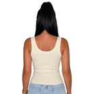 A woman viewed from the back wearing a fitted scoop-neck tank top in a light cream color, paired with light blue jeans, against a plain white background.