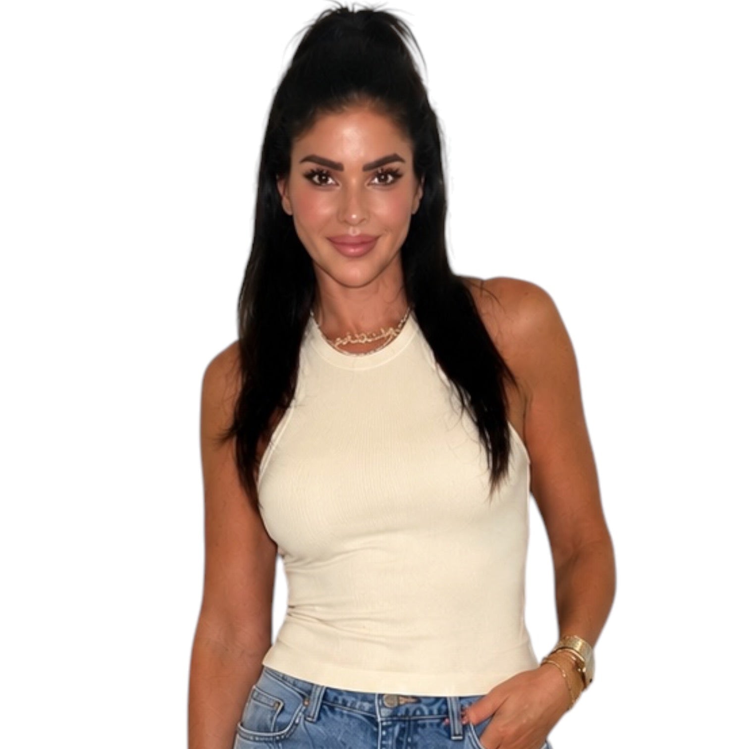 A woman with long dark hair in a high ponytail wearing a fitted cream-colored ribbed halter top and blue jeans, standing against a plain white background.