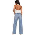 A woman shown from the back wearing light-wash wide-leg denim jeans and a white halter top, photographed against a plain white studio background.