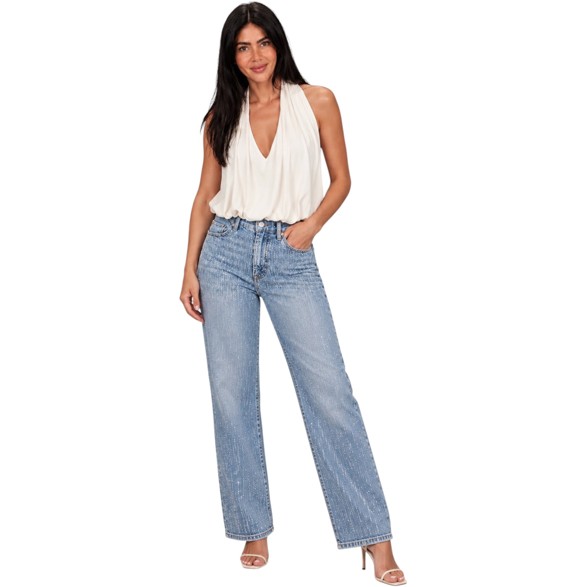 A woman modeling light-wash blue wide-leg jeans with a cream halter top, standing against a plain white background.