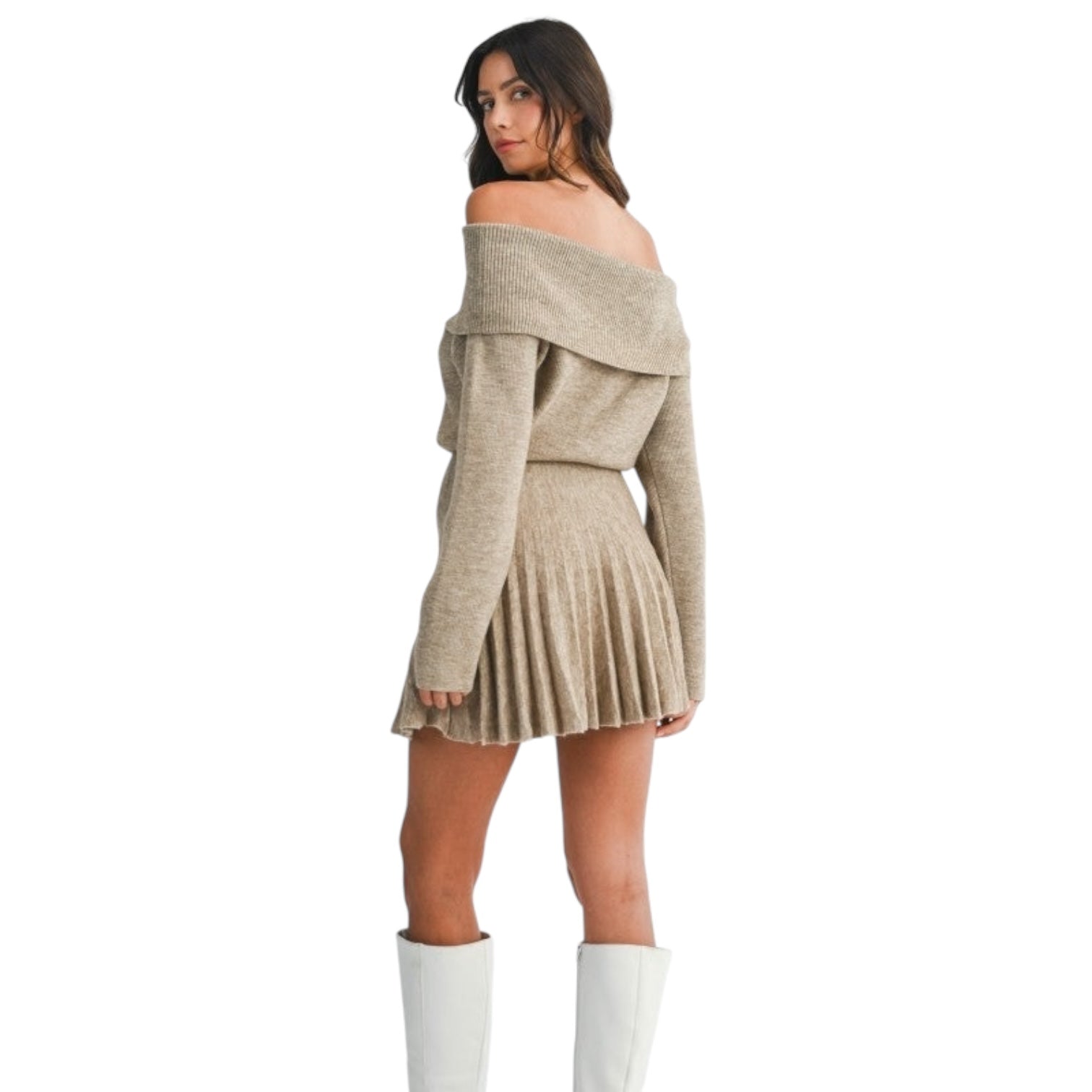 Woman wearing a beige off-shoulder sweater dress with white boots on a white background