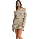 Woman wearing a beige off-shoulder sweater dress on a white background