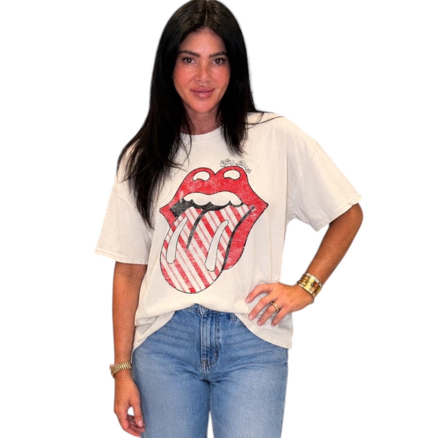 A woman modeling an oversized white graphic t-shirt featuring the red and white Rolling Stones tongue-and-lips logo, paired with light blue jeans against a plain white background.