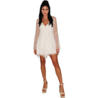 Woman wearing a white lace dress with sheer sleeves on a white background