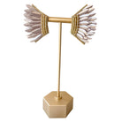 Gold earring stand with feathered earrings on a white background