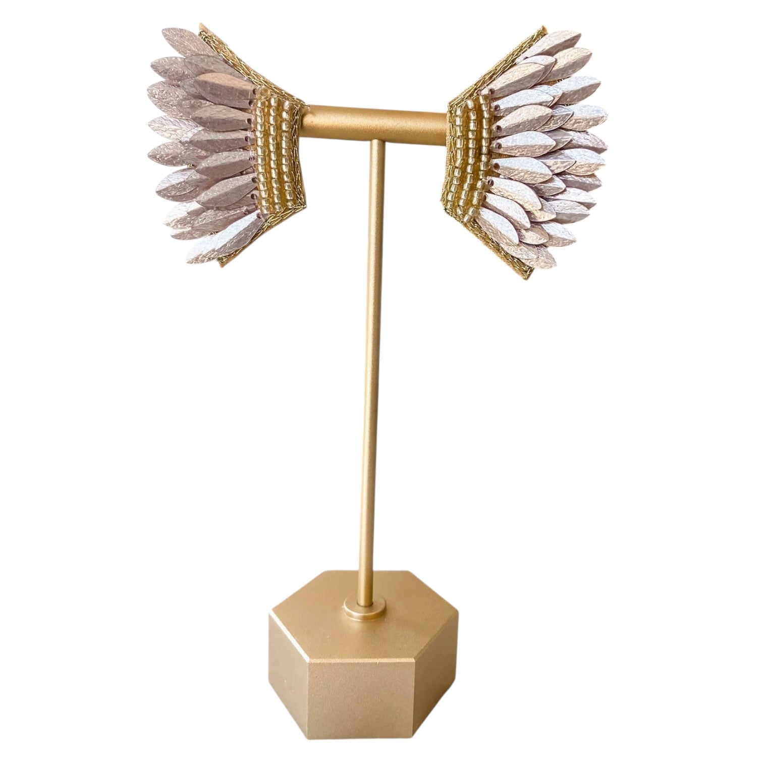 Gold earring stand with feathered earrings on a white background