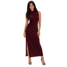 A woman modeling a sleeveless, high-neck, floor-length burgundy velvet dress with ruching and a thigh-high slit, paired with black high-heeled sandals, set against a plain white background.