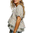 Woman wearing a floral blouse with ruffled layers on a white background