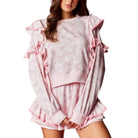 Pink lounge set with ruffled details on a white background