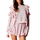 Woman wearing a pink floral set with ruffled details on a white background