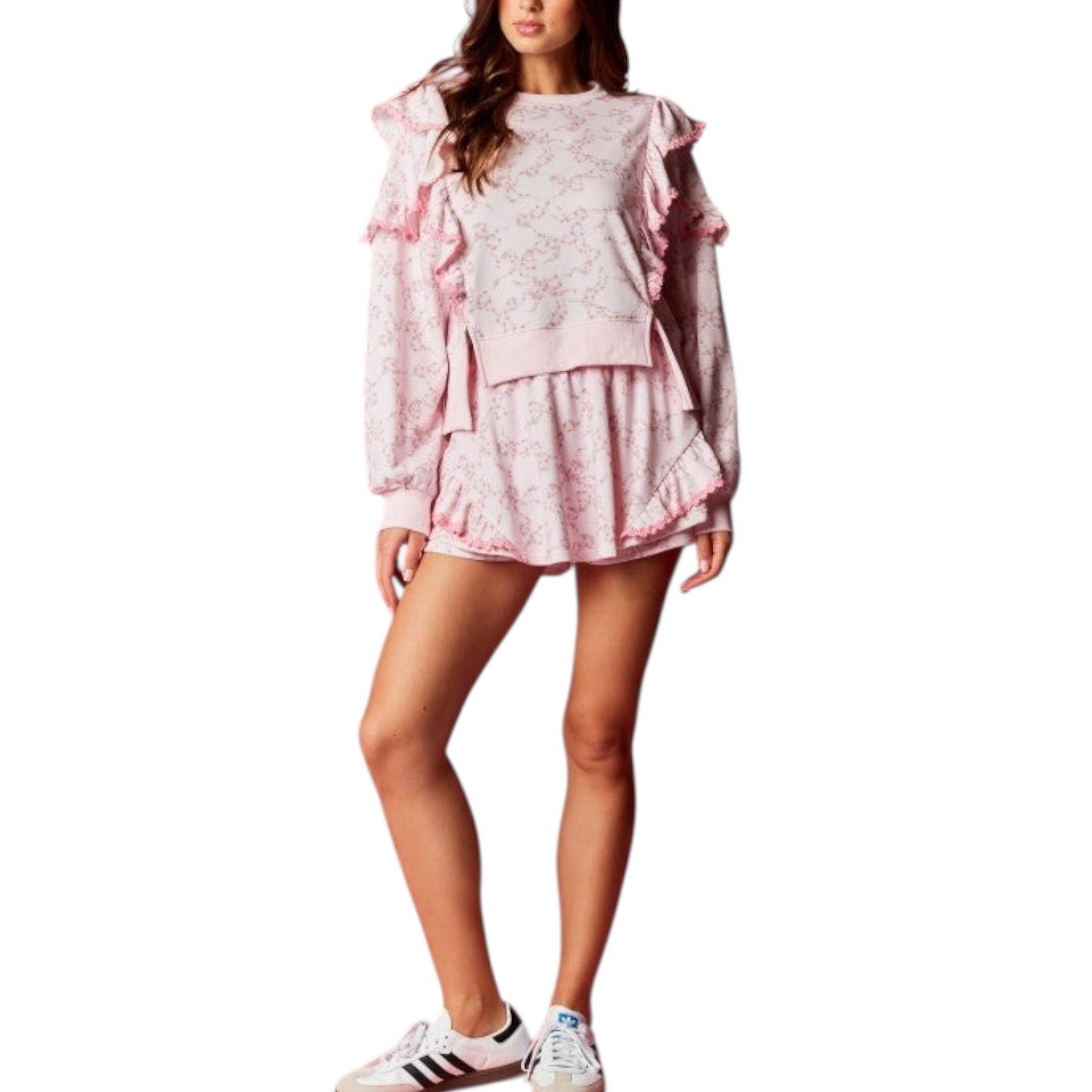 Woman wearing a pink outfit with ruffled sleeves and shorts on a white background