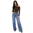 A woman modeling a dark brown off-the-shoulder long-sleeve crop top paired with wide-leg blue jeans and brown pointed shoes, set against a plain white background.