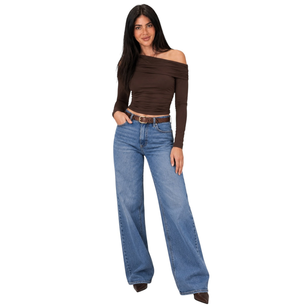 A woman modeling a dark brown off-the-shoulder long-sleeve crop top paired with wide-leg blue jeans and brown pointed shoes, set against a plain white background.