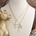 Gold necklace with a cross pendant on a mannequin bust, next to a gold animal figurine and decorative container.