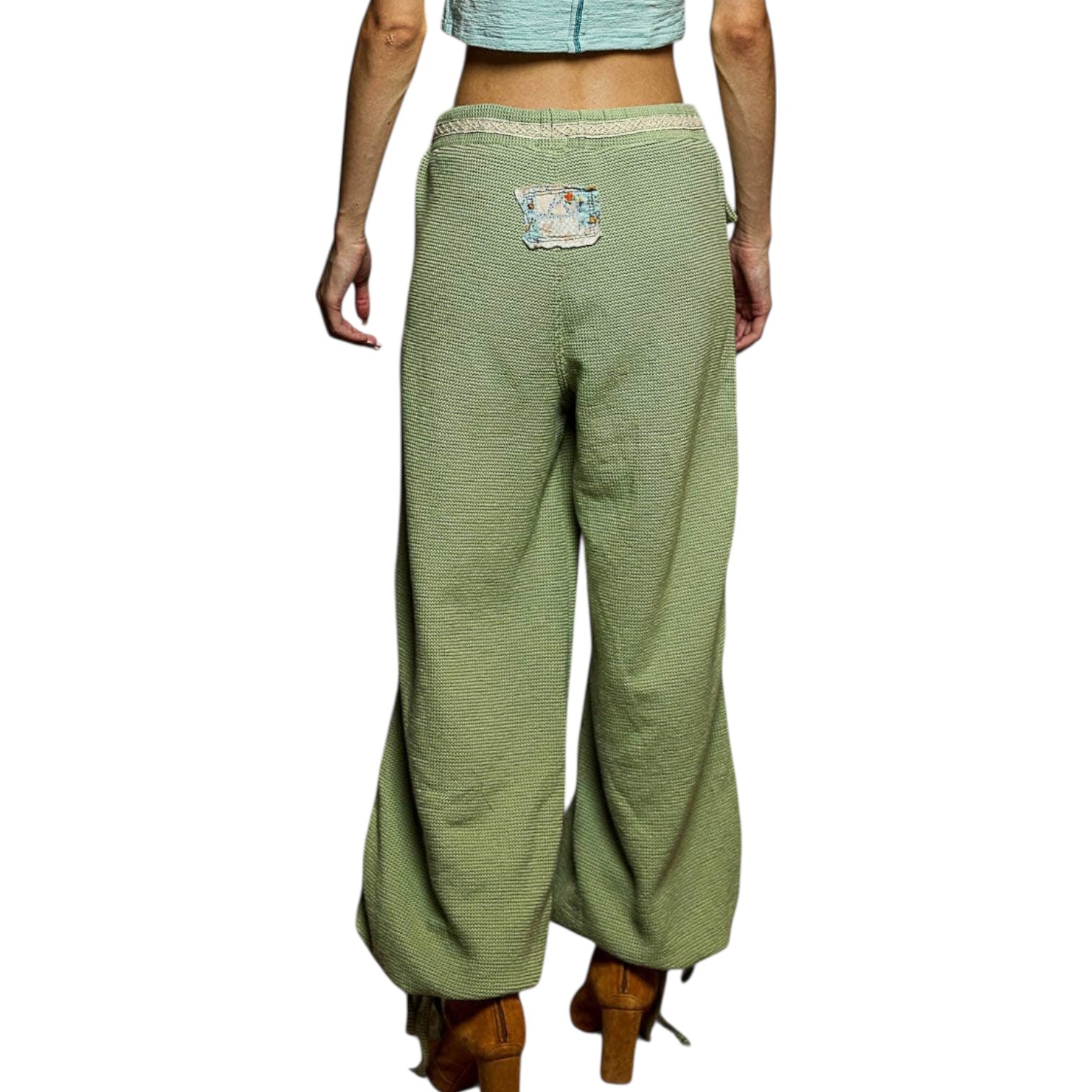 Green wide-leg pants worn by a person on a white background