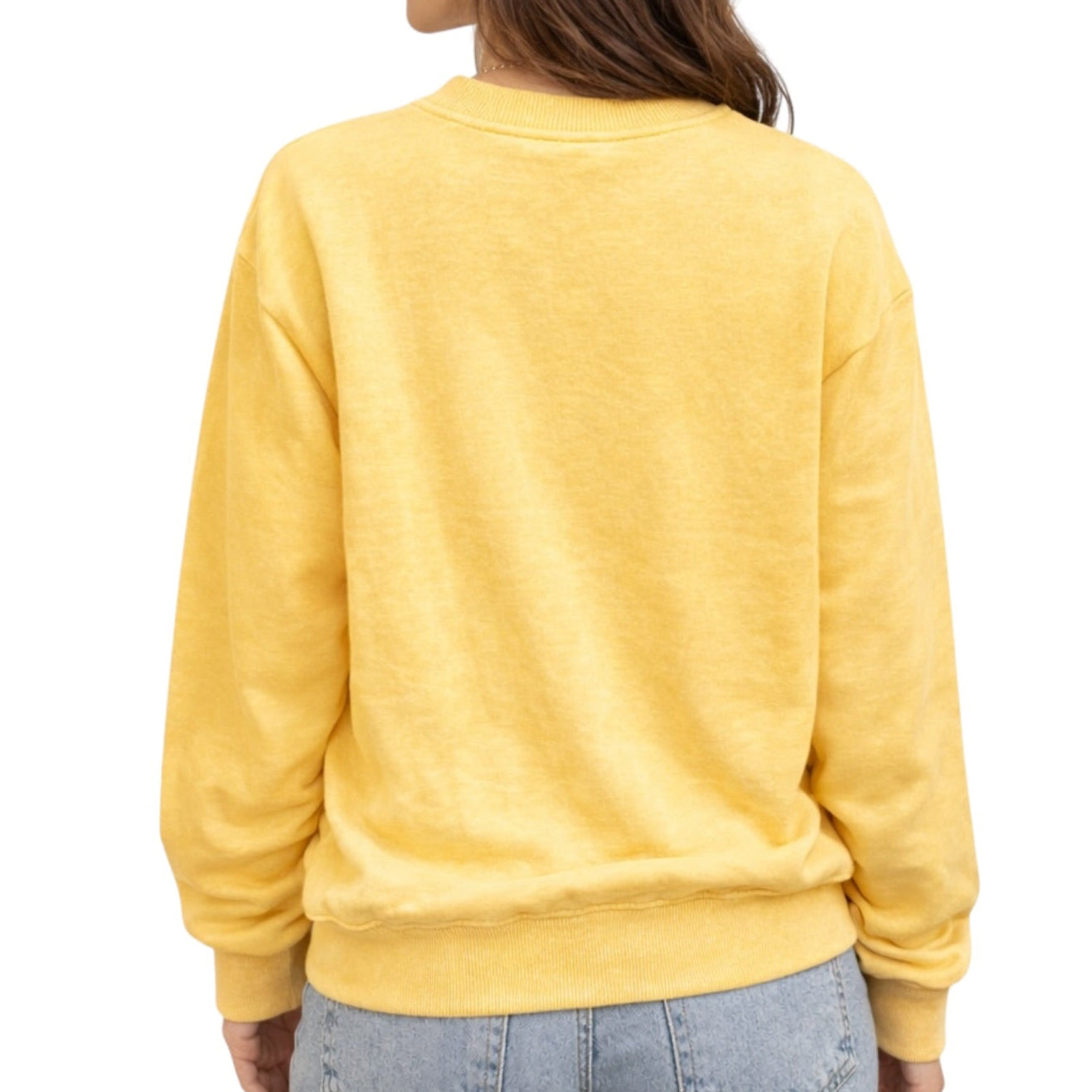 A person shown from the back wearing a pale yellow crewneck sweatshirt and light blue jeans against a plain white background.