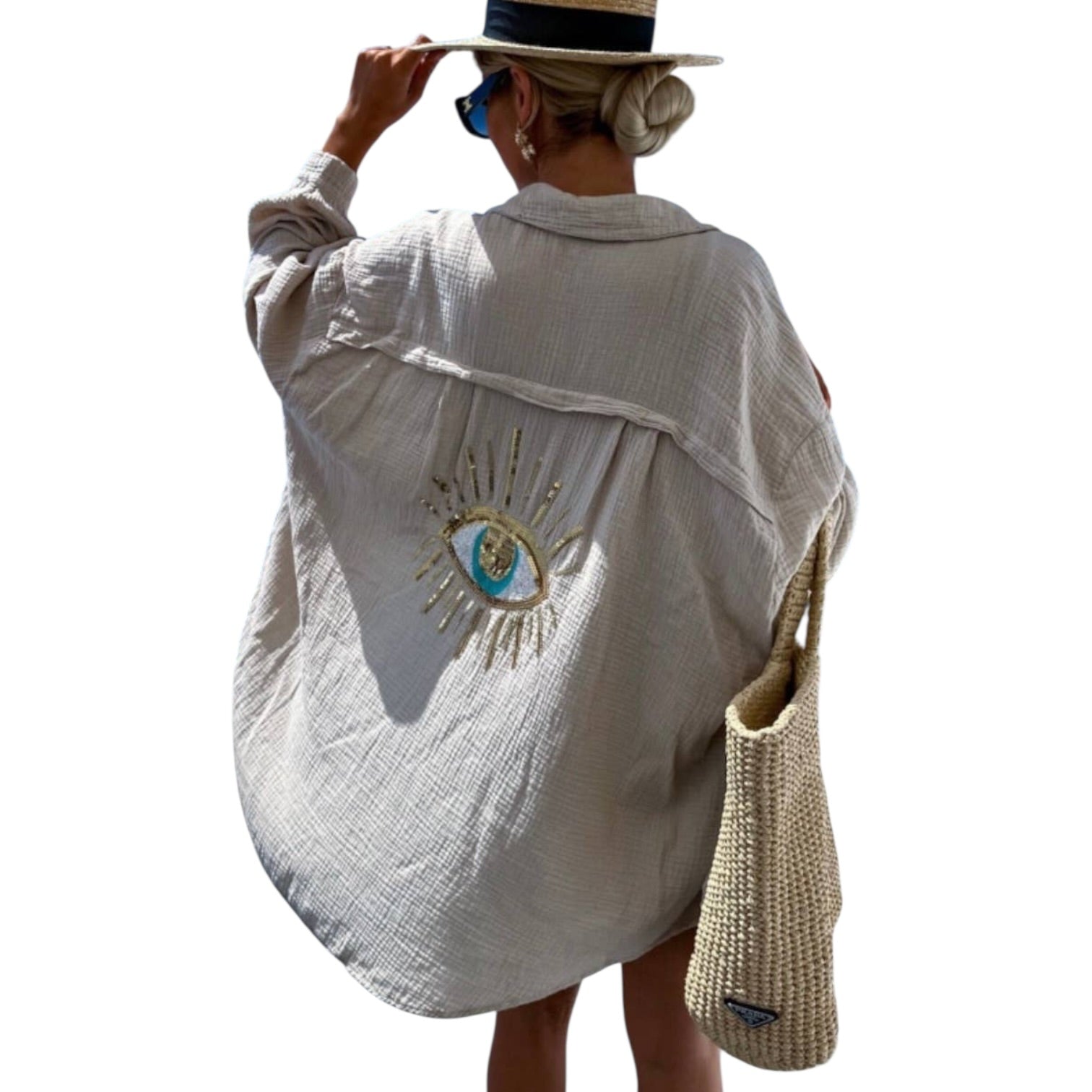 Person wearing a white shirt with an eye design and holding a straw bag on a white background