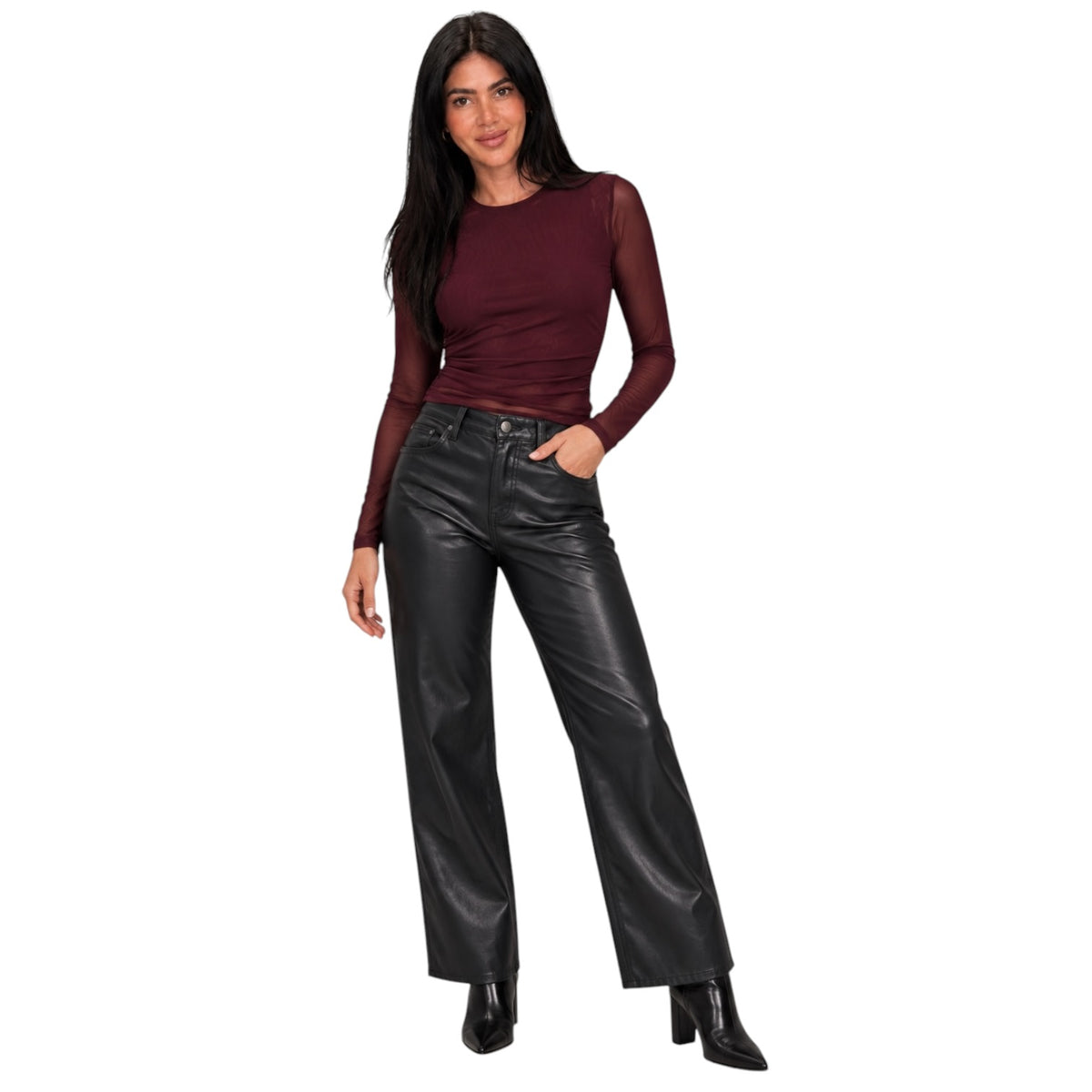 A woman modeling a dark burgundy long-sleeve top with sheer mesh sleeves and black wide-leg faux leather pants, standing against a plain white background.
