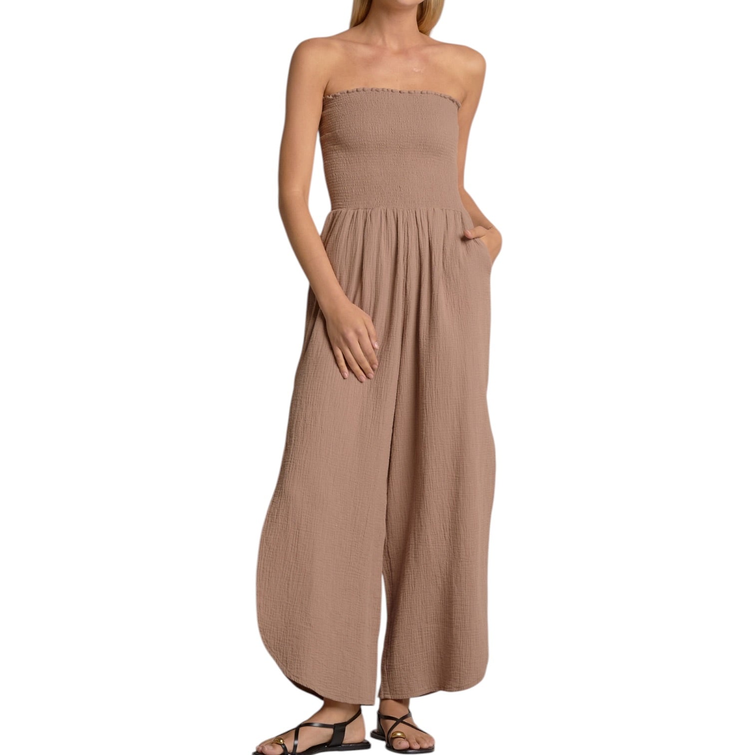 Woman wearing a beige strapless jumpsuit on a white background