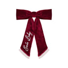 A festive Santa Claus-themed velvet bow accessory, featuring a deep burgundy red velvet finish with white faux-fur trim at the ends and 'Santa Baby' embroidered in white script on one of the tails.