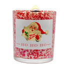 A festive Christmas candle in a clear glass jar filled with white wax and red sprinkles, featuring a vintage Santa illustration and the text 'Merry Christmas' and 'HO HO HO' on the front label.