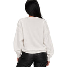 A woman viewed from the back wearing an off-white crewneck sweatshirt and black pants, set against a plain white background.