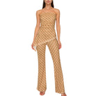 Woman wearing a beige strapless jumpsuit with a subtle pattern on a white background