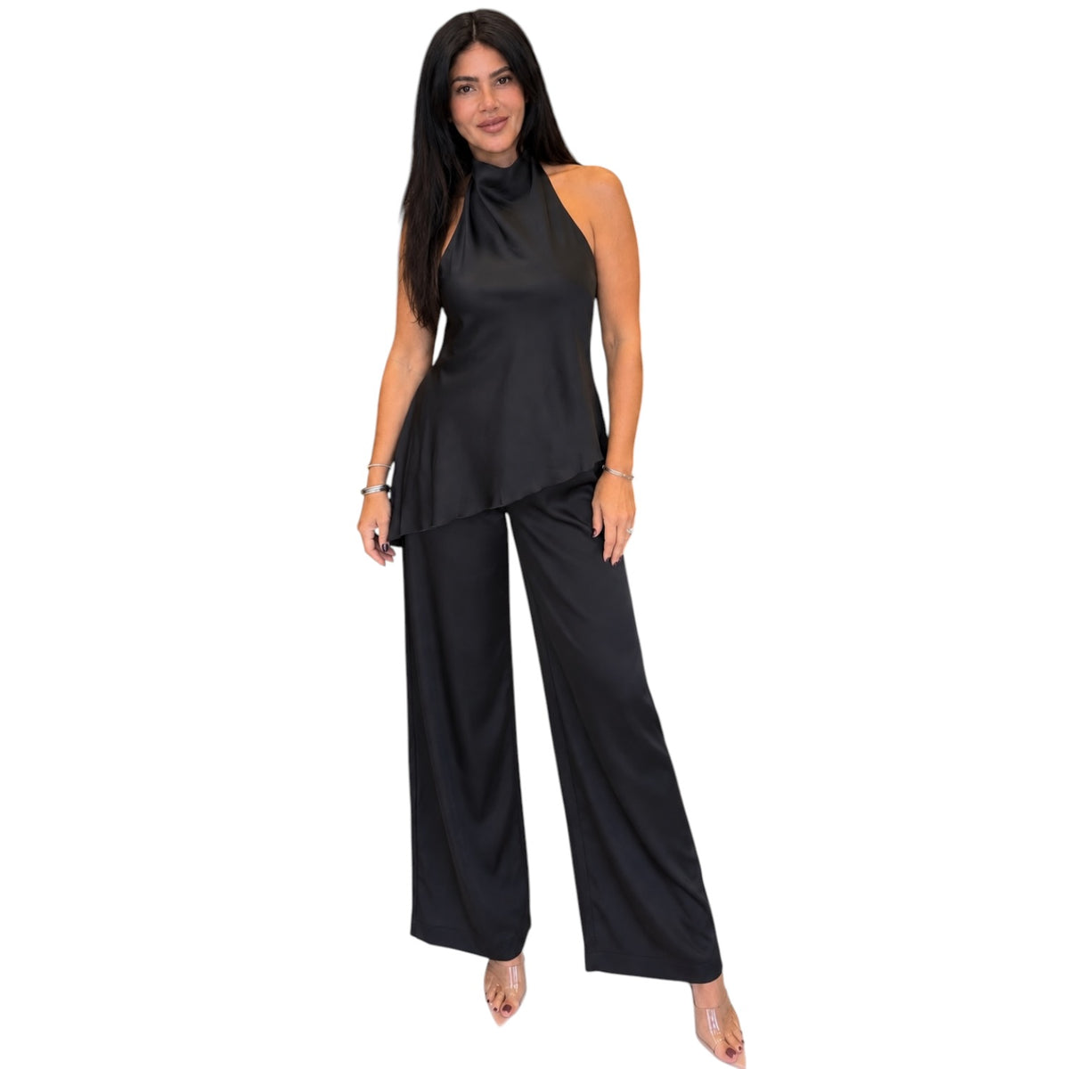 A woman modeling a black satin halter-neck top and matching wide-leg pants set against a plain white background.