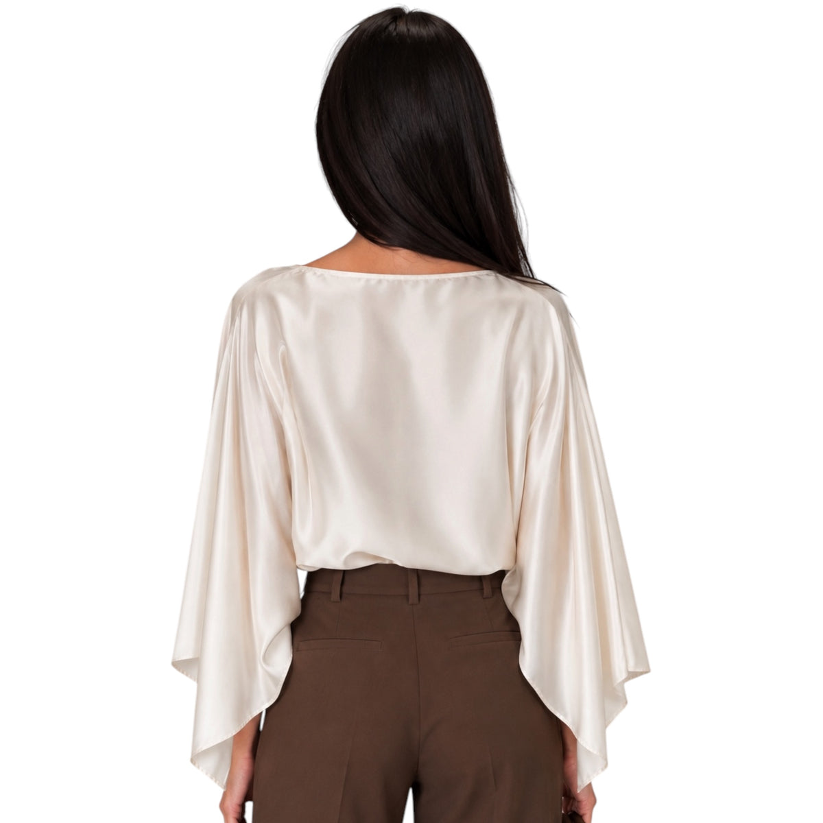 A woman viewed from the back wearing a cream satin long-sleeve top with wide draped sleeves and brown trousers, set against a plain white background.