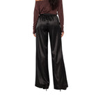 A model shown from the back wearing shiny black wide-leg satin pants and a dark brown off-the-shoulder top against a plain white background.