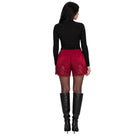 A woman shown from the back wearing a black long-sleeve top, red lace-trimmed shorts, sheer black tights, and black knee-high boots against a plain white background.