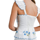 White dress with blue floral embroidery and trim on a white background