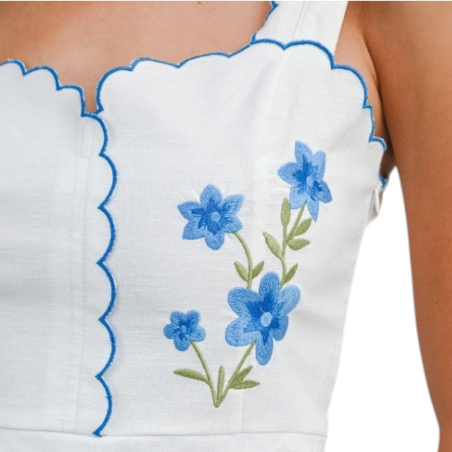 White top with blue floral embroidery on a white background