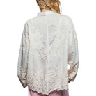 Light-colored lace blouse worn by a person on a white background