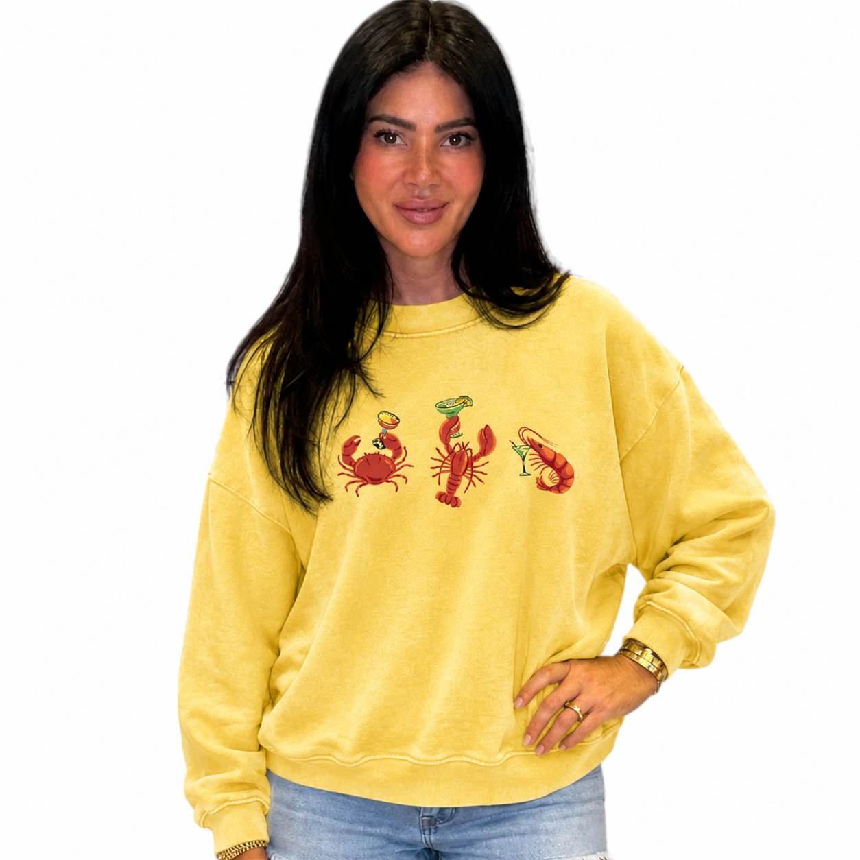 Woman wearing a yellow sweatshirt with red lobster designs on a white background