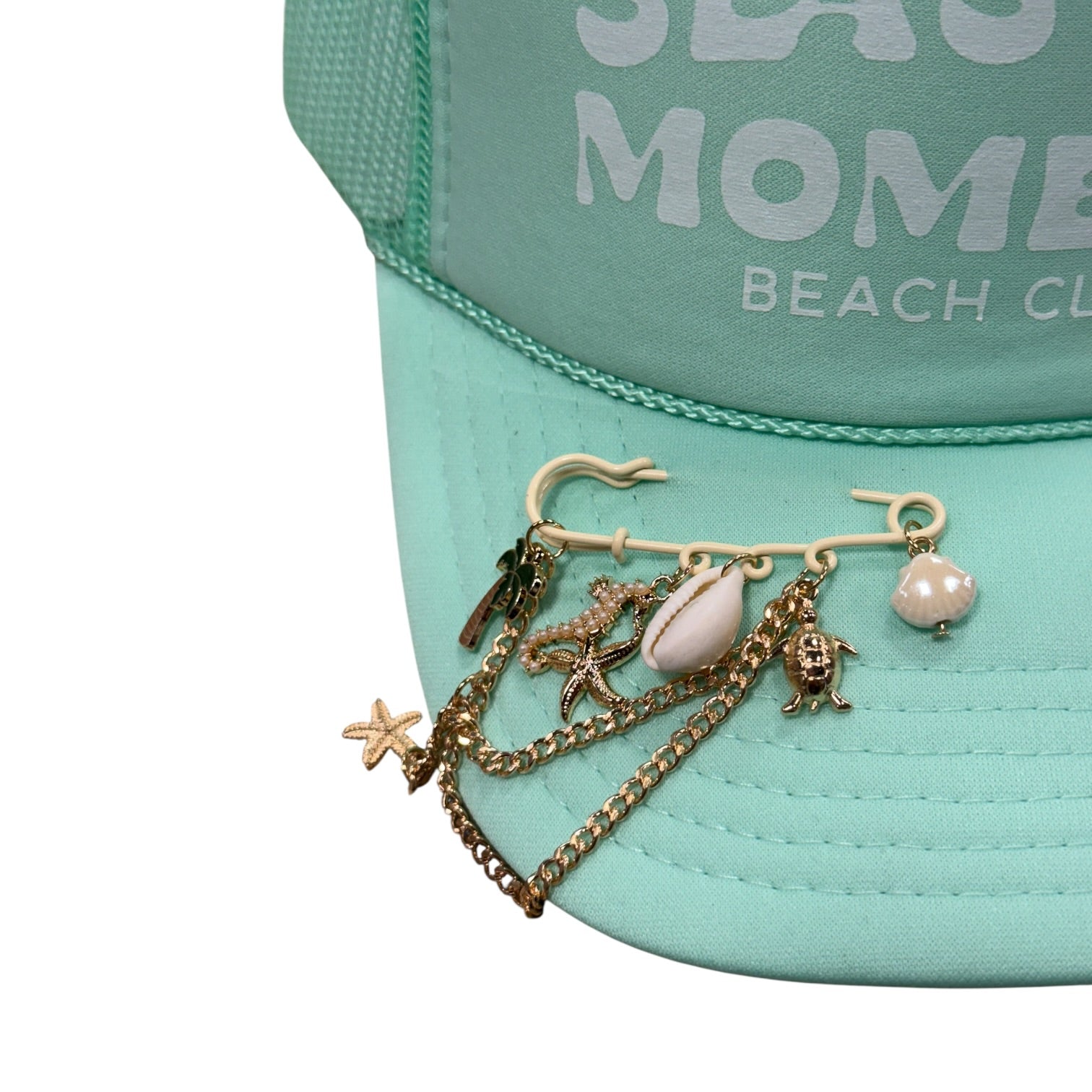 Mint green cap with 'Sea Mom Beach Club' text and charm necklace on a white background