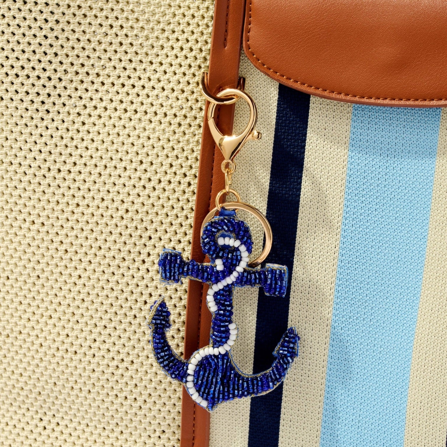 Blue beaded anchor keychain attached to a striped bag.