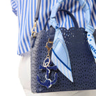 Navy handbag with anchor charm and matching scarf, worn by a person in a blue and white striped shirt.