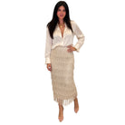 A woman modeling a cream satin long-sleeve blouse and a matching cream fringe midi skirt against a plain white background.