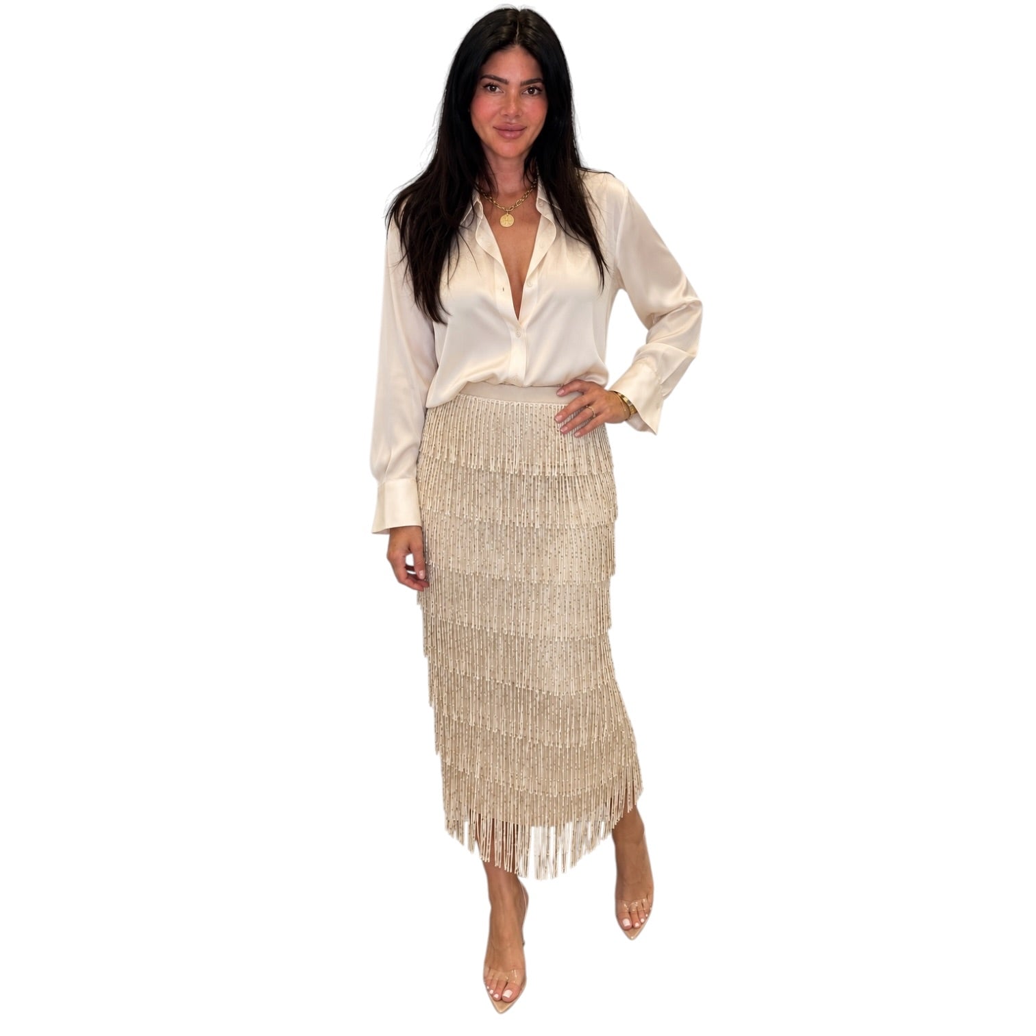 A woman modeling a cream satin long-sleeve blouse and a matching cream fringe midi skirt against a plain white background.