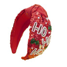 A festive red sequined headband featuring the word 'HO HO HO' in white rhinestone lettering, decorated with green holly leaves and small white pearl accents, shown on a plain white background.