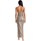 A woman shown from the back wearing a strapless, sequined halter maxi dress in a metallic champagne gold color, paired with nude high heels, against a plain white background.