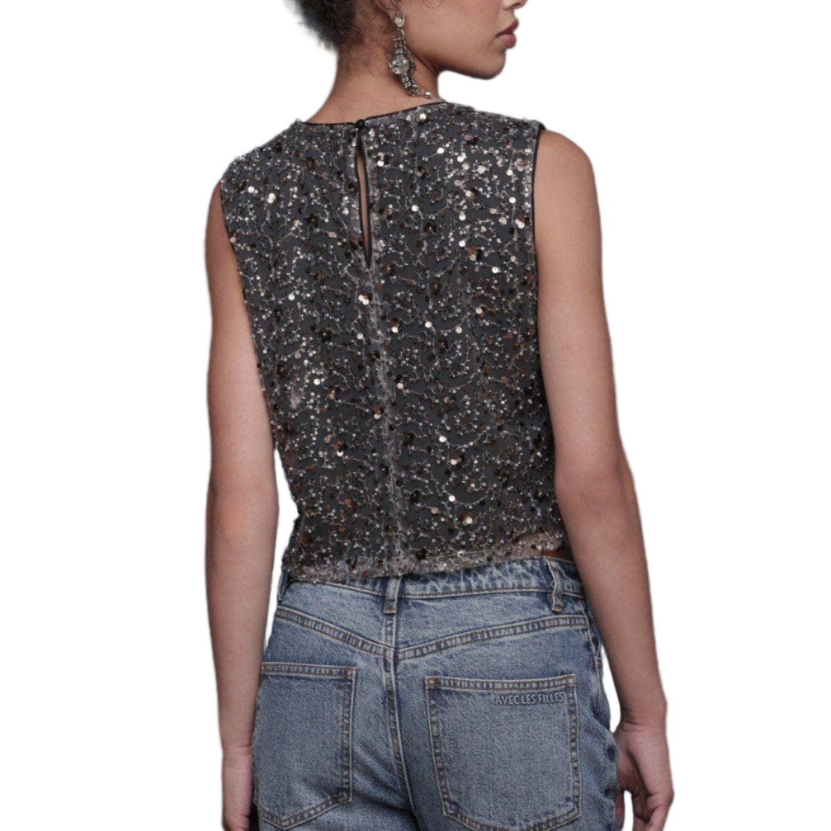 Person wearing a sequined top and jeans on a white background