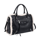 A black faux leather handbag with a cream-colored shearling lining, featuring dual top handles, a front zip pocket, and silver-tone hardware, shown against a plain white background.